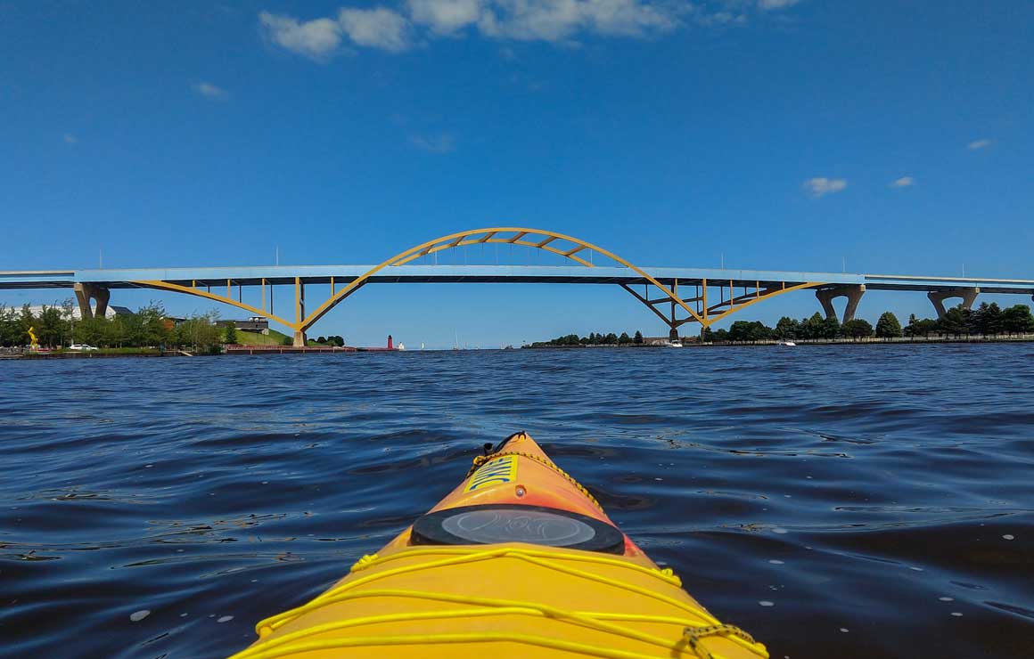 Isaacs Family Ltd. The front of a kayak on the river near the Hoan bridge.