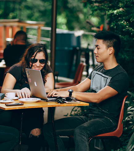 Two people work at a table outdoors.