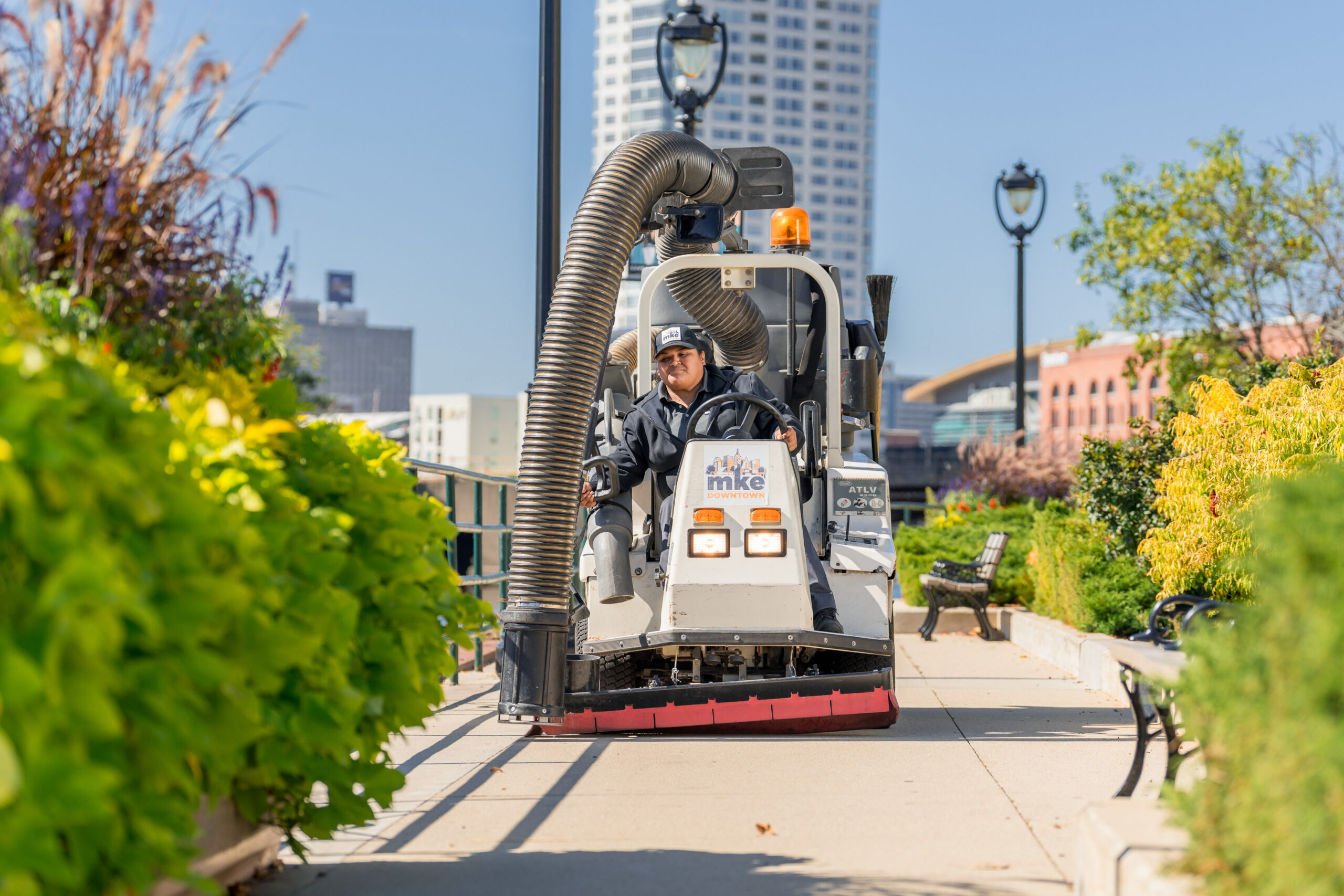 A Clean Sweep Ambassador drives a sidewalk cleaner along the riverwalk.