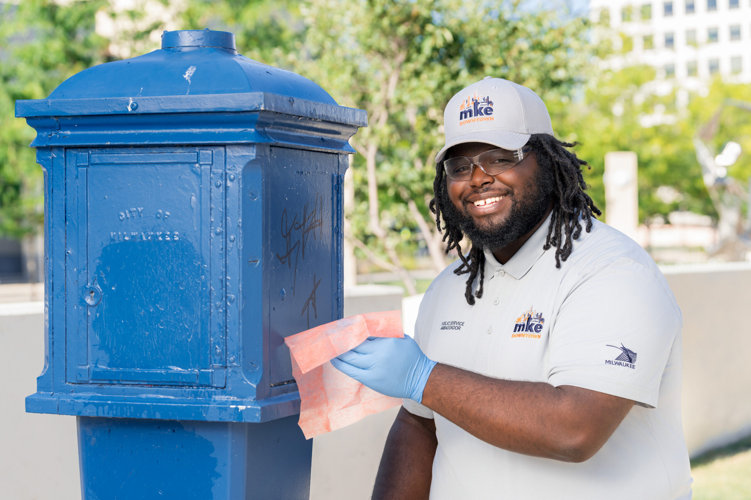 A Public Service Ambassador cleans graffiti off of an old blue police callbox in Milwaukee.