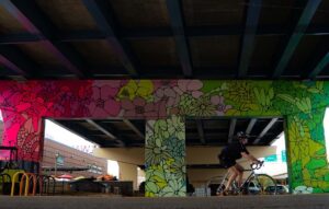 A mural under an overpass that features bright flowers.