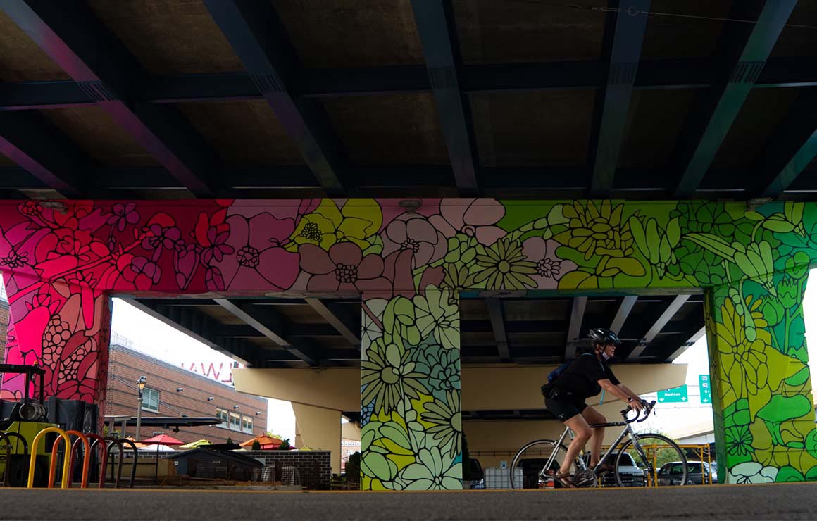 A mural under an overpass that features bright flowers.