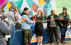 The artist cuts the ribbon at a ceremony celebrating the new mural.