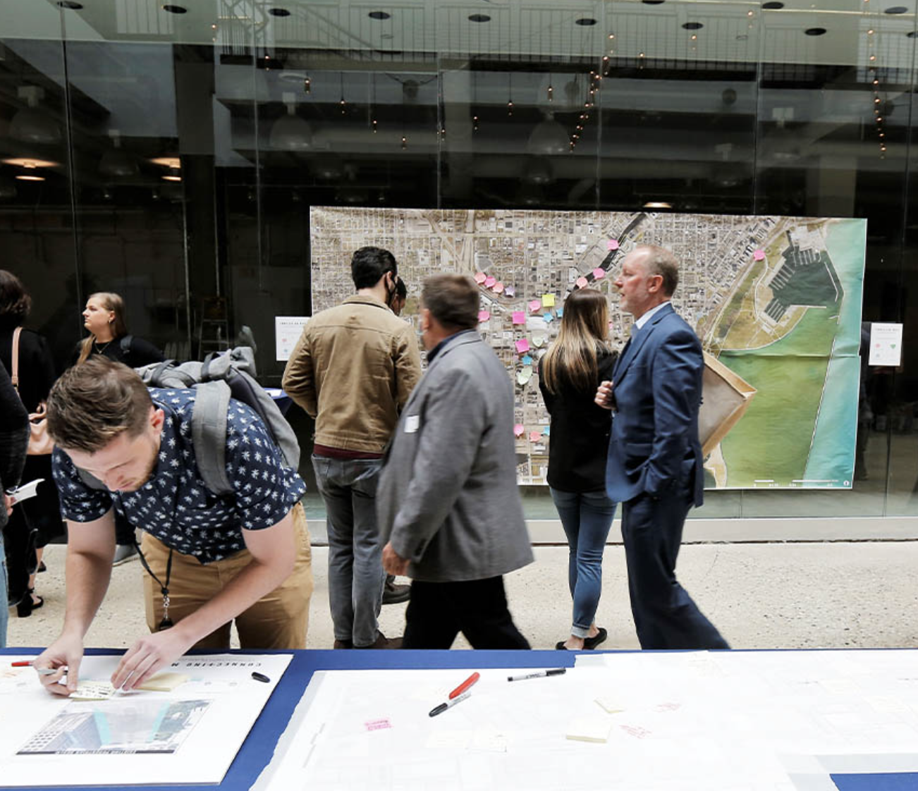 People look at a map with post-in notes on it at a community meeting.