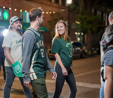 A group of Bucks fans walking across the street.