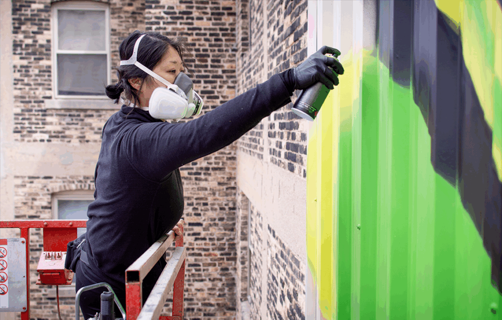 Westown Gateway Mural_Ossers2 Artist Emma Daisy Gertel spray paints part of her mural.