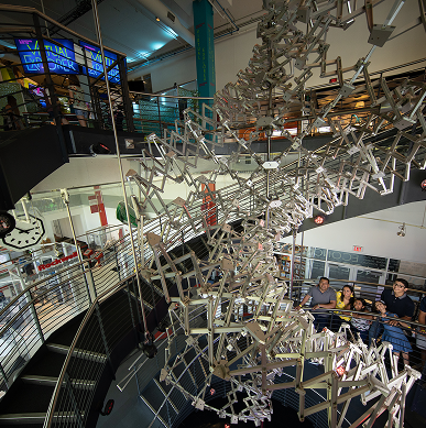 A family looks up at a two-story metal installation at Discovery World.