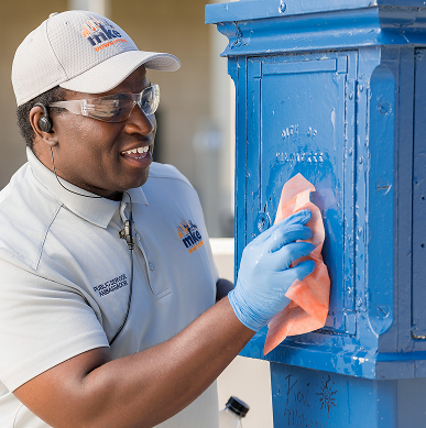A Public Service Ambassador cleans an old Milwaukee police call box.