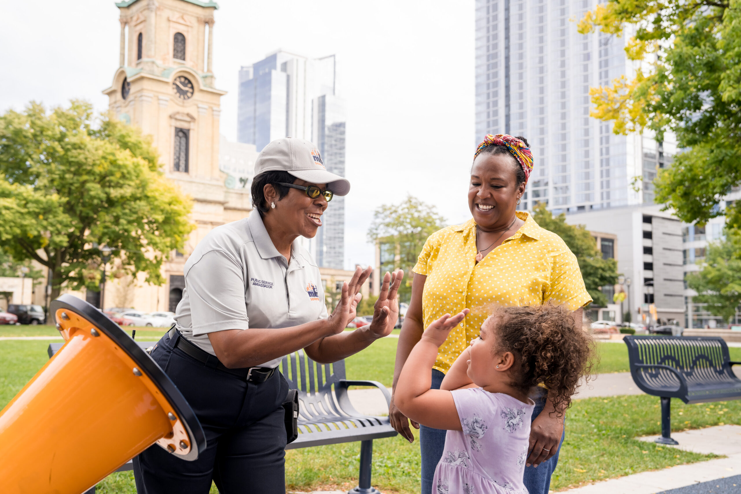 A Public Service Ambassador high fives a little girl.