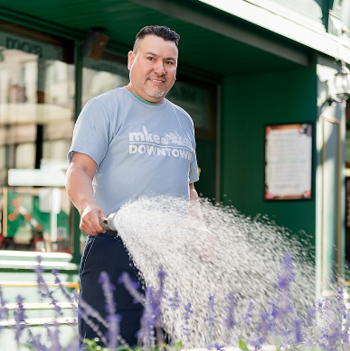 A member of the landscape crew waters flowers in Milwaukee.