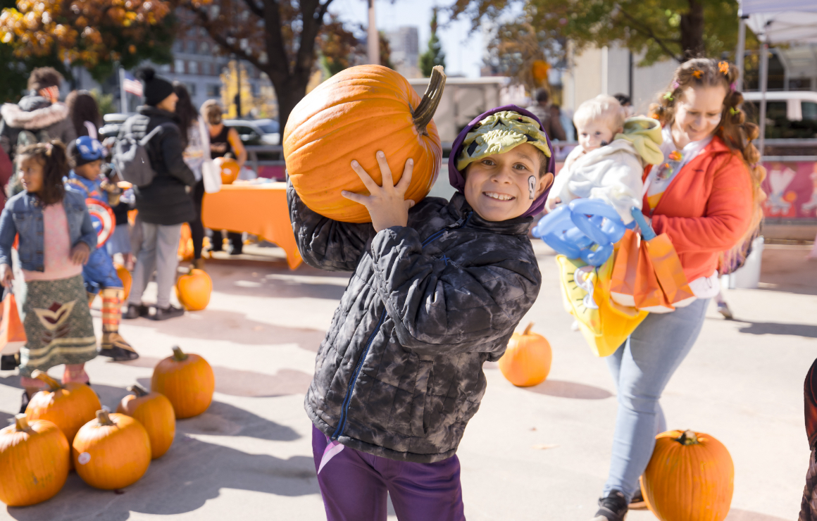 A young boy holds up his pumpkin.