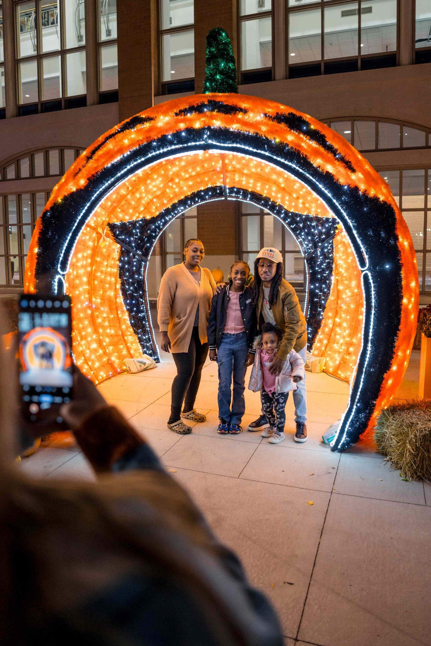 Someone takes a photo of a family in front of Halloween lights.