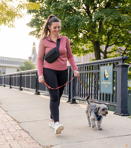 A woman walks her dog along the Milwaukee riverwalk.