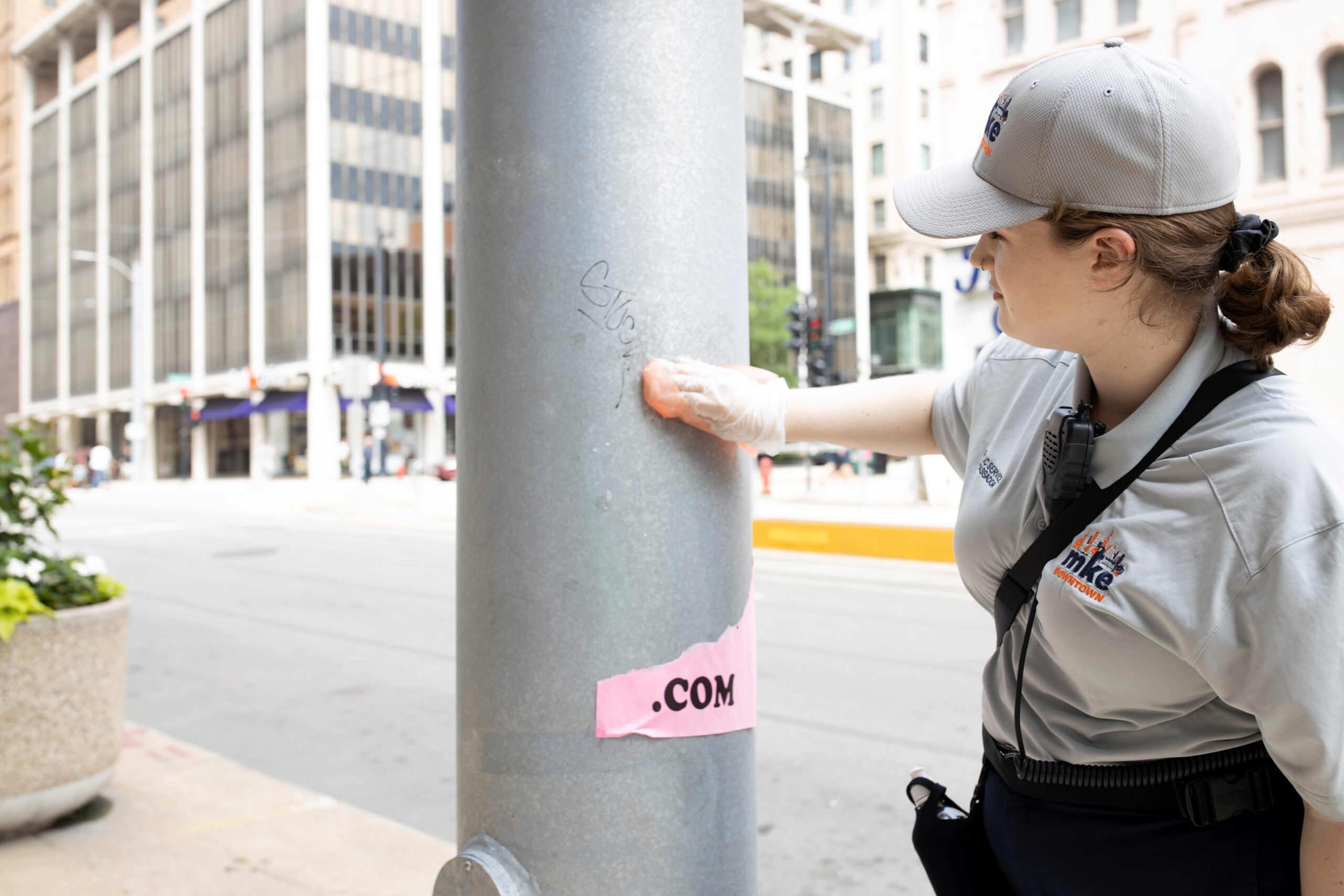 A member of the graffiti removal team wiping away graffiti on a light post.